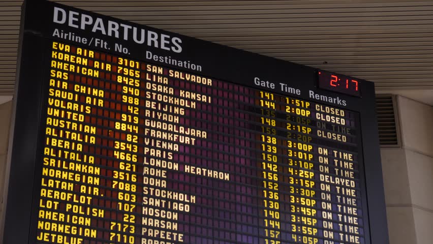 Classic split-flap style departures board (FIDS) at LAX, showing international flights to global cities like London, Paris, and Rome. Displays gate times and status.