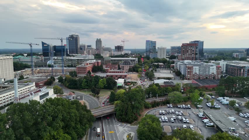 City of Raleigh, North Carolina, with tall buildings, wide streets, and green areas captured at sunset.