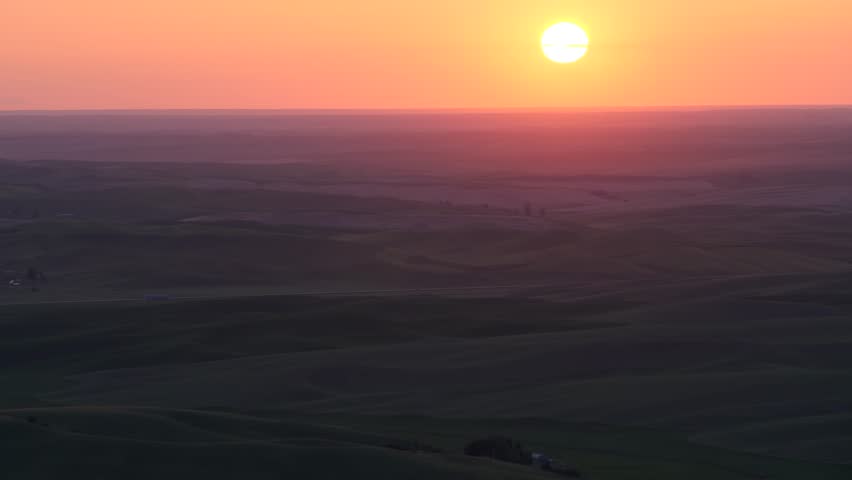 Serene drone video captures the breathtaking sunset over Nevada's Great Basin plains. The vibrant sky bathes the rolling terrain in warm, golden hues, creating a tranquil scene.