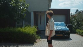 Youth guy goes home, Adolescent strolls towards vehicle in peaceful residential setting during daytime, Teenager walking calmly toward stationary car amid suburban greenery in bright summer - Powered by Shutterstock - Get 15% off with code: PIKWIZARD15