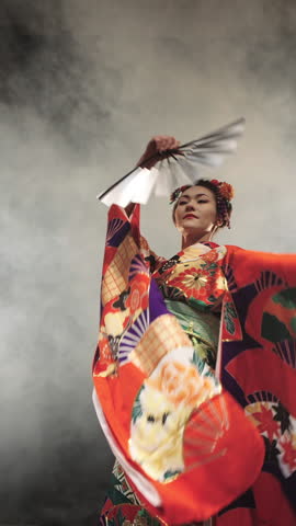 Japanese Geisha In Red Embroidered Kimono With Golden Fan Performing Graceful Turn In Studio Smoke Creating Flowing Motion Of Sleeves Symbolizing Art Of Movement And Timeless Japanese Elegance