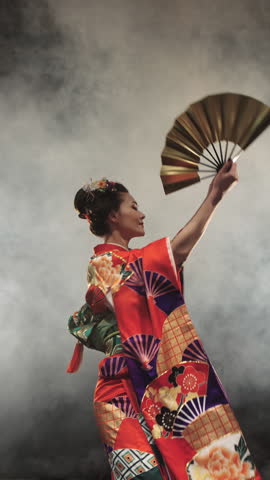 Japanese Geisha In Red Embroidered Kimono With Golden Fan Performing Graceful Turn In Studio Smoke Creating Flowing Motion Of Sleeves Symbolizing Art Of Movement And Timeless Japanese Elegance