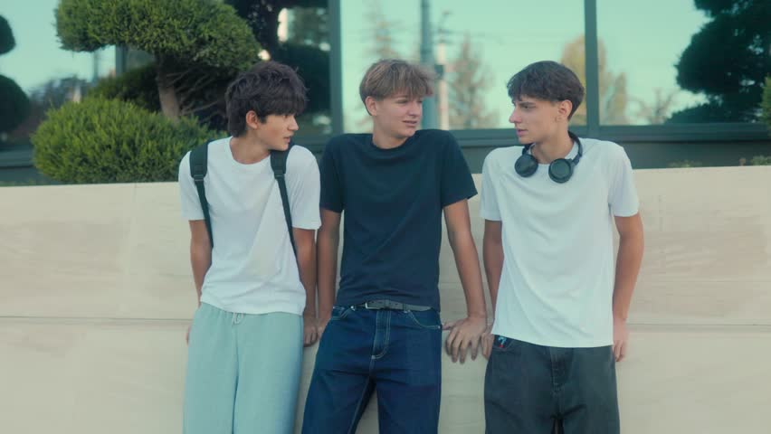 Group of teenage boys sitting outdoors, laughing and enjoying casual talk. Friendship, carefree vibe, and youthful emotions highlight a relaxed summer lifestyle.
