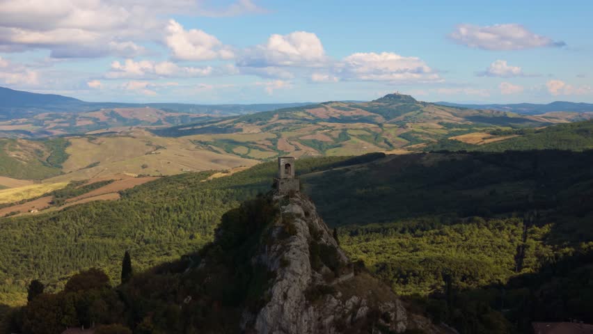 Ancient stone chapel ruins crown the rocky peak of Campiglia d’Orcia, Siena, Tuscany, Italy. Aerial