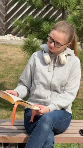 A young woman reading a book on a walk. 
