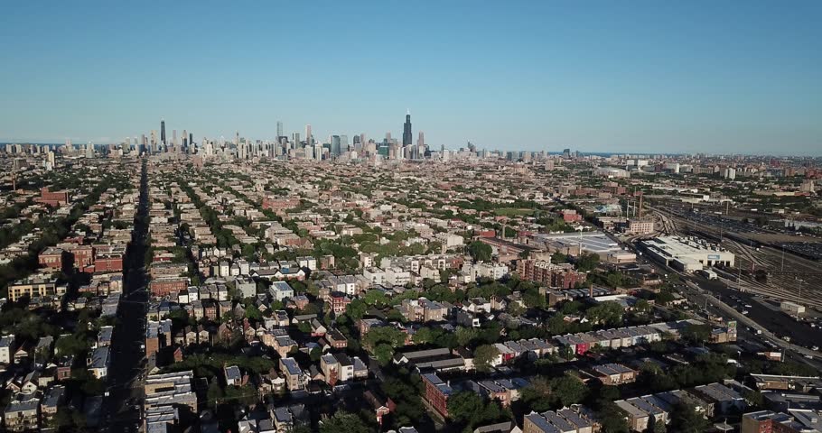 Aerial drone video from the suburbs showing the Chicago, Illinois skyline on the distant horizon as the drone is flying to the right.