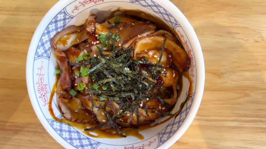 Hand uses spoon and fork to scoop grilled pork rice bowl under bright, natural lighting