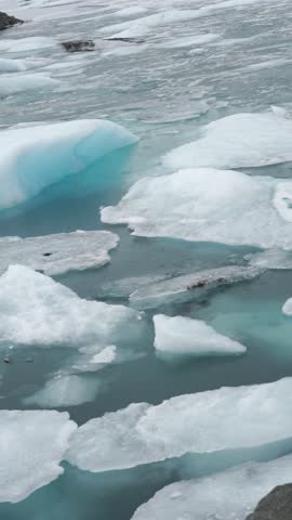 Cold blue icebergs slowly floating and breaking in arctic waters near a glacier