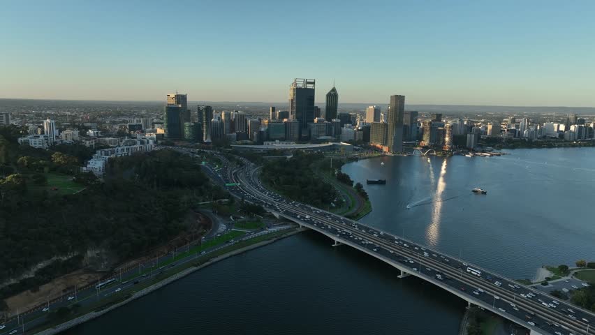 Aerial view of a bridge bustling with traffic towards the skyscrapers reflecting the sunlight, alongside the Swan River, Perth, Western Australia, Australia.