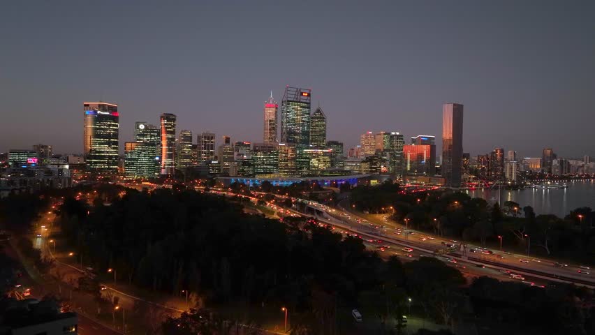Aerial view of the Perth CBD skyline, its buildings illuminated at dusk, with roads and traffic visible below, Perth, Western Australia, Australia.