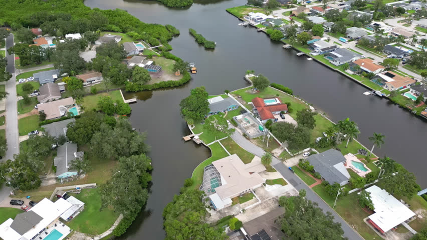 Aerial overview of a suburban neighborhood lining canals and waterways with a cluster of mangrove trees nearby in Largo, Florida