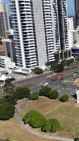 Drone glides above Gold Coast skyscrapers, highway, convention center, and coastline in bright daylight