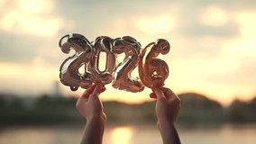 Hands holding golden balloon numbers 2026 with sunset light, happy new year celebration and future concept, hope and success idea for holiday greeting and new beginning with warm golden atmosphere - Powered by Shutterstock - Get 15% off with code: PIKWIZARD15