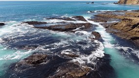 Aerial view of ocean waves crashing against rocky tidepools along the rugged coastline of Laguna Beach, California - Powered by Shutterstock - Get 15% off with code: PIKWIZARD15