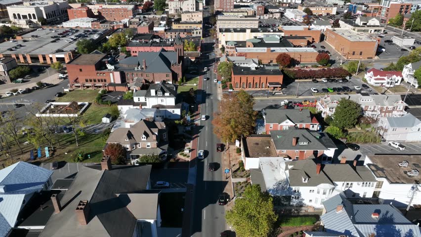 Driving cars own main street leading to downtown of Harrisonburg,Virginia.Aerial tilt up wide shot. Sunny day with blue sky in historic american town. Panorama view.