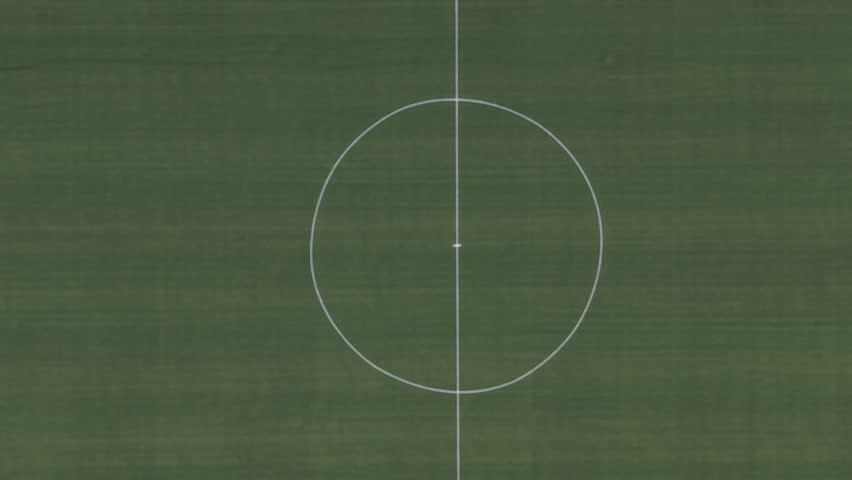An Aerial top view of a green football field with clear white boundary lines and center circle