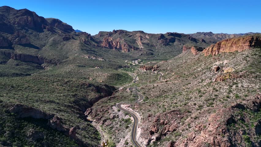 Aerial view of the winding Apache Trail road cutting through the rugged terrain near the Superstition Mountain, Apache Junction, Arizona, United States.