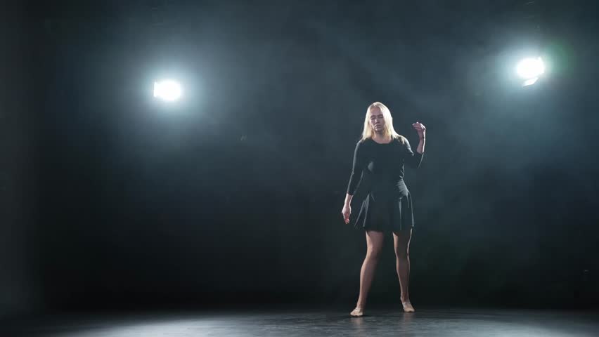 Contemporary woman dancer posing on black background with smoke. Adult female artist performer dancing with expression. Modern ballerina dancing in darkness. Passion dance in dark. Flexibility balance