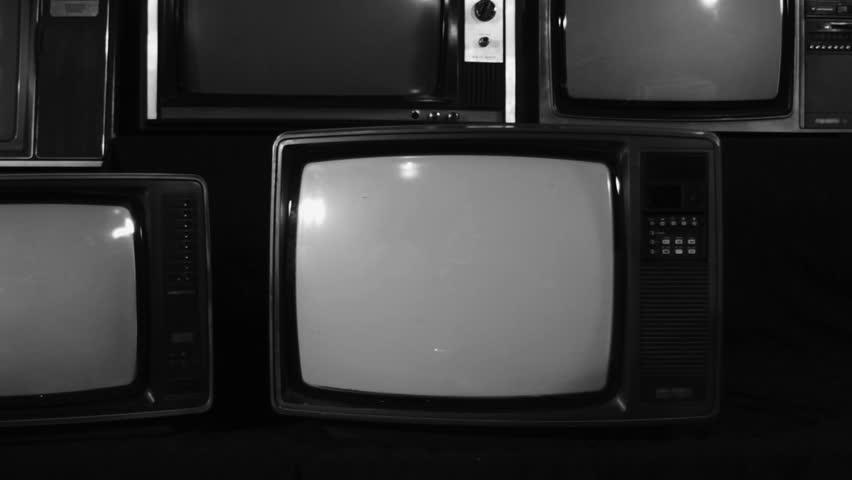 Black and White Retro TV Turning On with Green Screen, Surrounded by Old Turned Off Televisions - Close Up