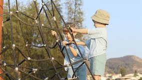 Tight shot of kids climbing a rope frame near the shore, capturing concentration and playful teamwork. Clip supports themes of growth, outdoor activity and summer exploration. Boys ascending rope maze - Powered by Shutterstock - Get 15% off with code: PIKWIZARD15