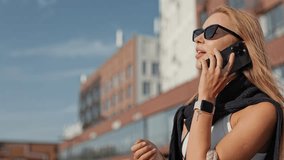 Caucasian woman with long hair wearing sunglasses. Spending time outside. Talking on smartphone and raising hand when noticing someone. Getting distracted by friend. Holding handbag on shoulder. - Powered by Shutterstock - Get 15% off with code: PIKWIZARD15