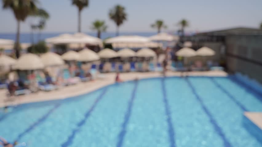  Two people toasting with refreshing fruit cocktails by a swimming pool. Concept of vacation.