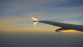 View of an airplane wing from the window, flying high above the clouds during a beautiful golden hour sunset. Serene and scenic sky view from a passenger's perspective. - Powered by Shutterstock - Get 15% off with code: PIKWIZARD15