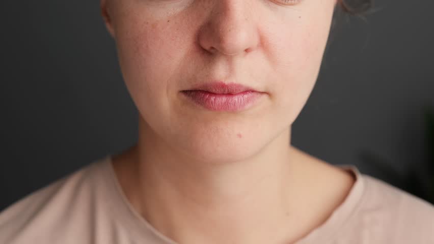 A woman struggles with nasal congestion, holding a tissue tightly to her nose in a serene indoor space during the morning hours