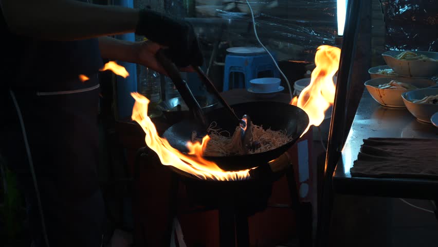 Street Chef Cooking Pad Thai with Flames in Wok at Bangkok Chinatown Night Market