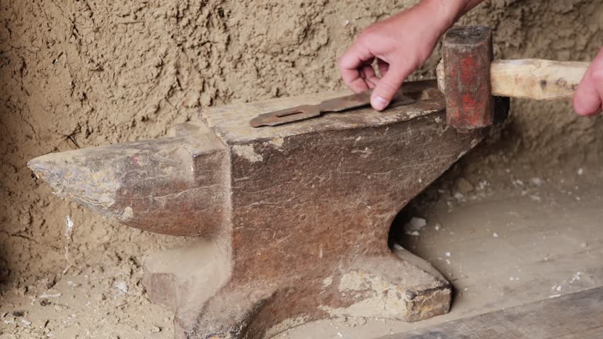 A skilled artisan shapes metal using a hammer on an anvil in a rustic workshop, showcasing traditional blacksmithing techniques and craftsmanship