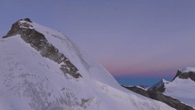 A breathtaking aerial view of the Allalinhorn moments before sunrise. Soft dawn light paints the snow-covered summit and surrounding Swiss Alps in warm pastel hues. - Powered by Shutterstock - Get 15% off with code: PIKWIZARD15