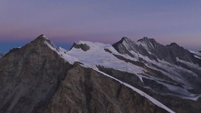 A breathtaking drone shot capturing the Allalin, Täschhorn, and Dom peaks moments before sunrise, bathed in soft pink skies and glowing alpine light over the majestic Swiss Alps. - Powered by Shutterstock - Get 15% off with code: PIKWIZARD15