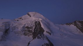 A breathtaking aerial view of the Allalinhorn moments before sunrise. Soft dawn light paints the snow-covered summit and surrounding Swiss Alps in warm pastel hues. - Powered by Shutterstock - Get 15% off with code: PIKWIZARD15