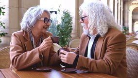 Elderly couple sitting together at outdoor cafe terrace drinking coffee and talking happily. Senior lifestyle, love, communication, relaxation, retirement leisure, companionship, conversation, warmth - Powered by Shutterstock - Get 15% off with code: PIKWIZARD15