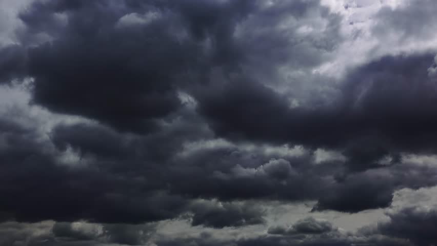 Time lapse of dramatic storm clouds moving across the sky with sunlight rays breaking through. 4K low angle view