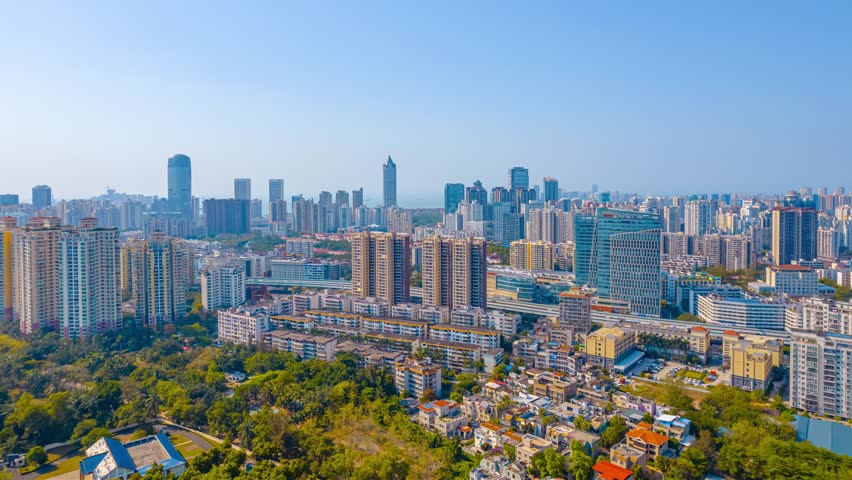 Aerial time lapse view of Haikou cityscape on Hainan Island, China, showcasing modern skyscrapers, residential buildings, and green spaces in the tropical island capital.