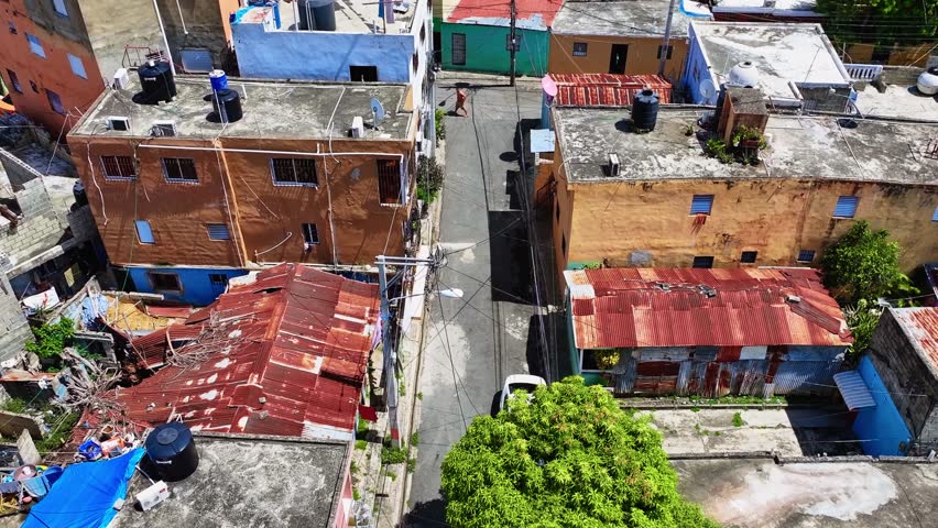 Life in the dilapidated houses of a dirty neighborhood in Santo Domingo. Rusty roofs of poor dwellings, aerial view. Life in the slums of the Dominican Republic. Social injustice.