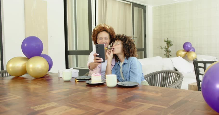 Couple marking birthday, lifting smartphone and feeding cake, generating crypto confetti and icons. Celebration, friendship, joy, festivity, digital, technology, lifestyle