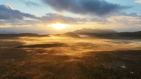 An aerial drone clip of the morning sun casting its light on a misty mountain valley, bathing the whole landscape in gold colour. - Powered by Shutterstock - Get 15% off with code: PIKWIZARD15