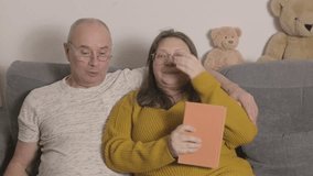 Happy husband and wife relaxing at home, Peaceful Elderly couple on sofa, woman reading book, man using laptop, cozy evening, quiet time, modern relationship, shared space, balanced relationship - Powered by Shutterstock - Get 15% off with code: PIKWIZARD15