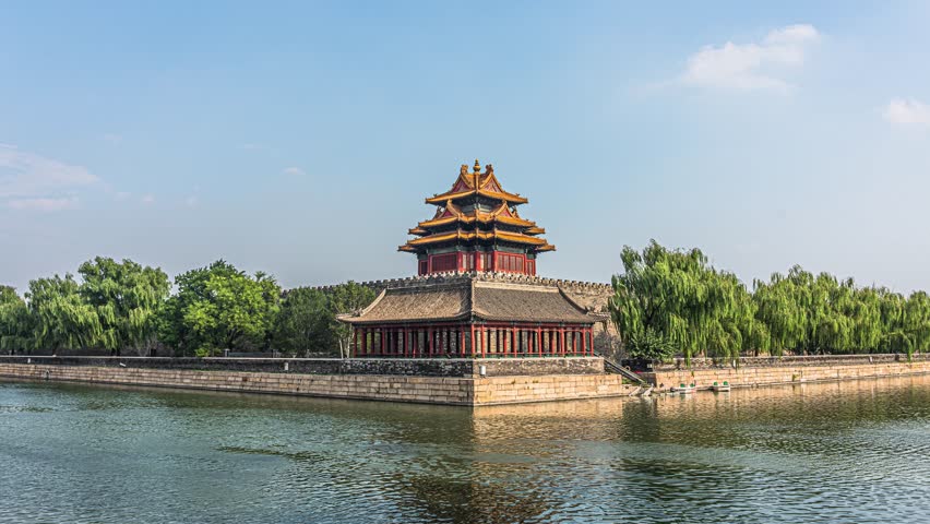 Traditional Chinese watchtower at corner of Forbidden City moat in Beijing, featuring classic imperial architecture with golden roofs reflected in calm water