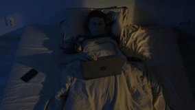 Man lying awake at night using laptop in bed, blue screen light causing insomnia - Powered by Shutterstock - Get 15% off with code: PIKWIZARD15