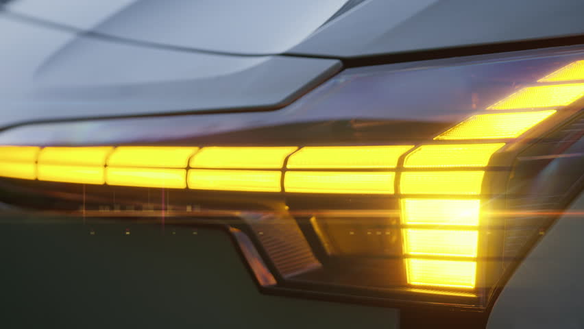 Close-up of yellow front turn signal flashing, car headlights, emergency lights