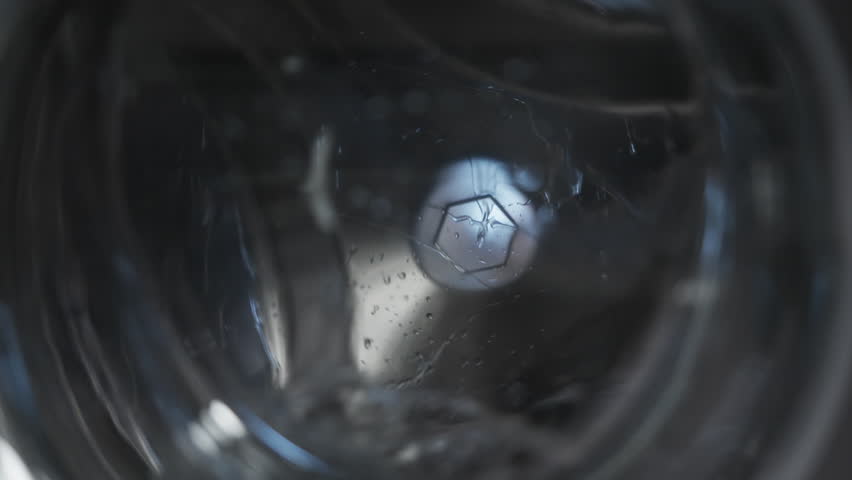 Slow motion of modern washing machine drum rotating, water splashing, close-up