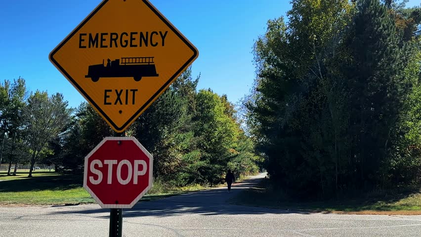 Two signs, Emergency Exit and Stop, are located on the Paul Bunyan Trail in Nisswa, Minnesota. The trail is popular with cyclists, walkers, runners, rollerbladers and snowmobilers.