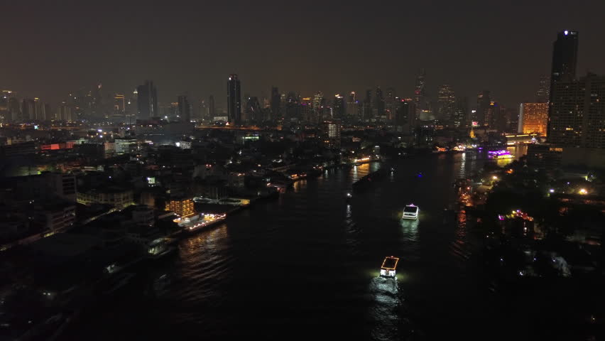 Aerial view of illuminated skyscrapers in Bangkok city and Chao Phraya River in night time, 4k