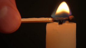 Lighting a candle with match over darkness. A hand holding a lighted match and lighting a white candle - Powered by Shutterstock - Get 15% off with code: PIKWIZARD15