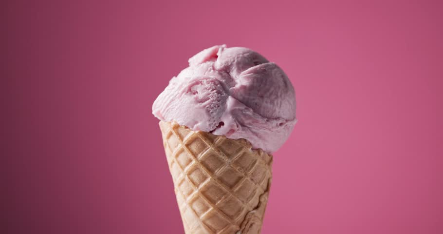 scoop of strawberry ice cream in a waffle cone rotating against a pink background, decorative sugar sprinkles falling on an icecream ball 