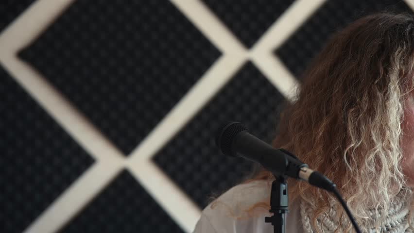 Caucasian woman singing into microphone in music studio. 