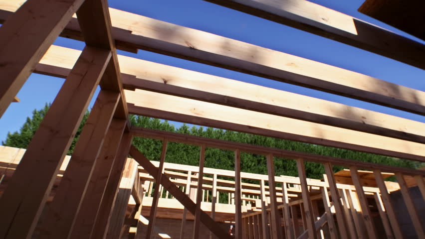 Workers are constructing wooden roof frame, rafters structure beams